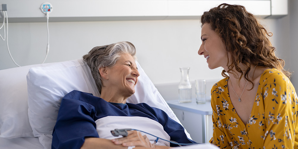 Daughter with mother at hospital bedside