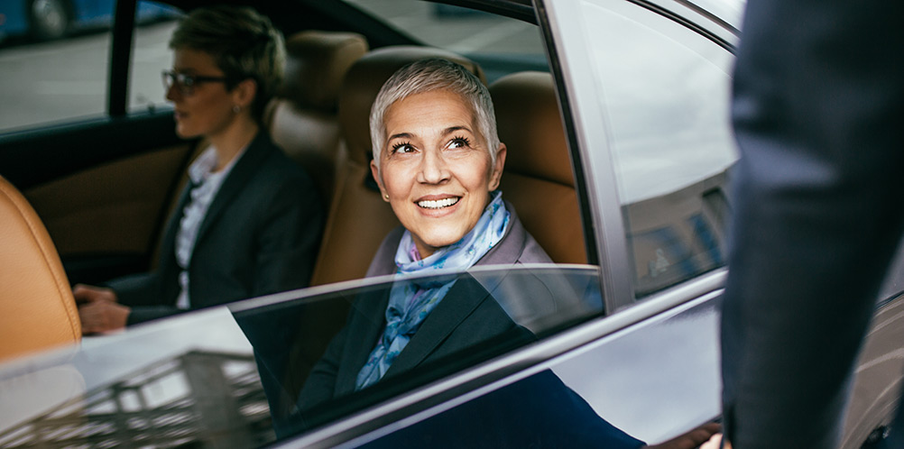 Smiling business woman looking out window to taxi driver