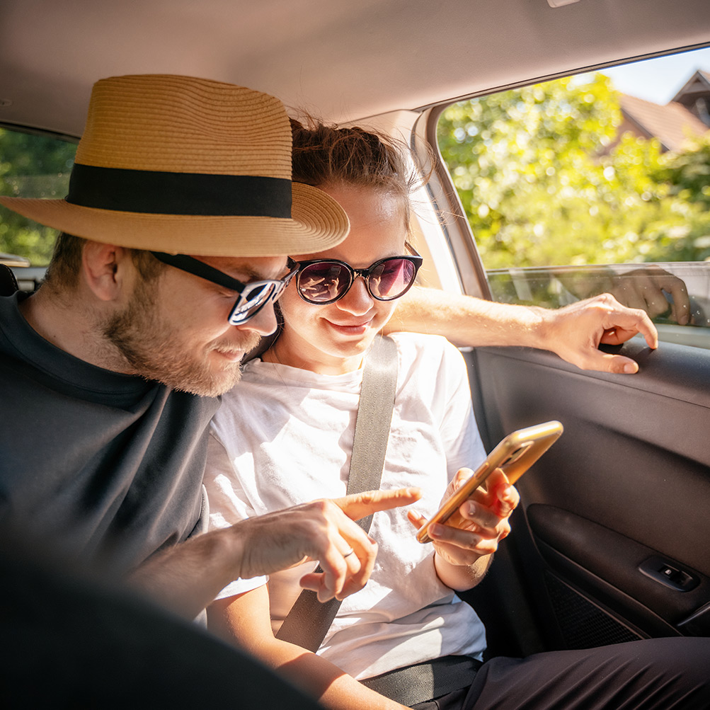 Couple looking at phone together while on long taxi journey